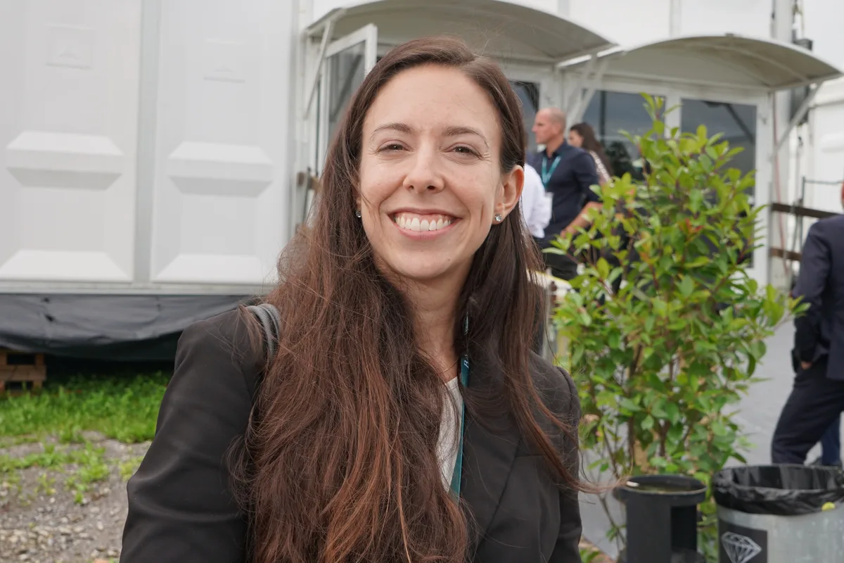 Eine dunkelhaarige Frau im dunklen Businessanzug.